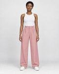 Model wearing the pink high-rise pleated wide-leg pants with a white tank top and white sneakers, front view