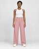 Model wearing the pink high-rise pleated wide-leg pants with a white tank top and white sneakers, front view