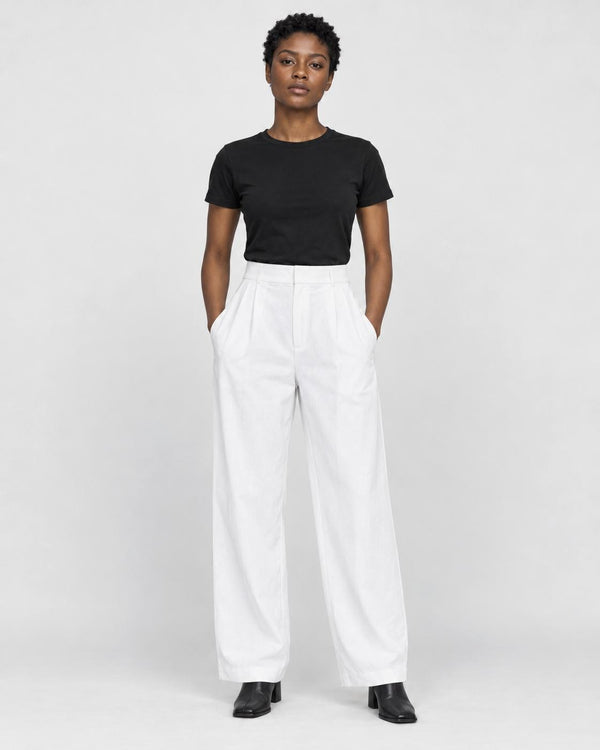 Model wearing the white high-rise pleated wide-leg pants with a black tee and black boots, front view