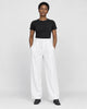 Model wearing the white high-rise pleated wide-leg pants with a black tee and black boots, front view