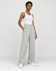 Model wearing the sage green high-rise pleated wide-leg pants with a white tank top and white sneakers, three-quarter view