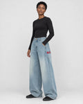 Woman in the light-blue wide-leg jeans turned slightly, showing the fade and the pocket lettering
