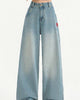 High-waisted light-blue wide-leg jeans with a lighter faded hem, hands crossed at the waist