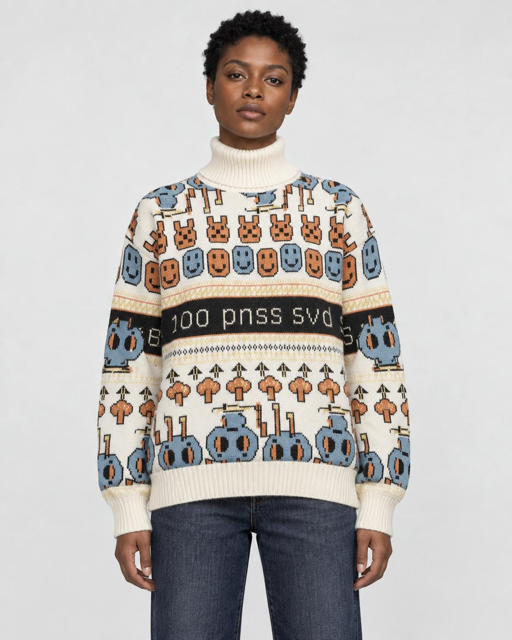 Model wearing the cream jacquard knit sweater with bunny and smiley face rows and a black lettering band, with dark jeans