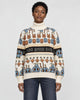 Model wearing the cream jacquard knit sweater with bunny and smiley face rows and a black lettering band, with dark jeans