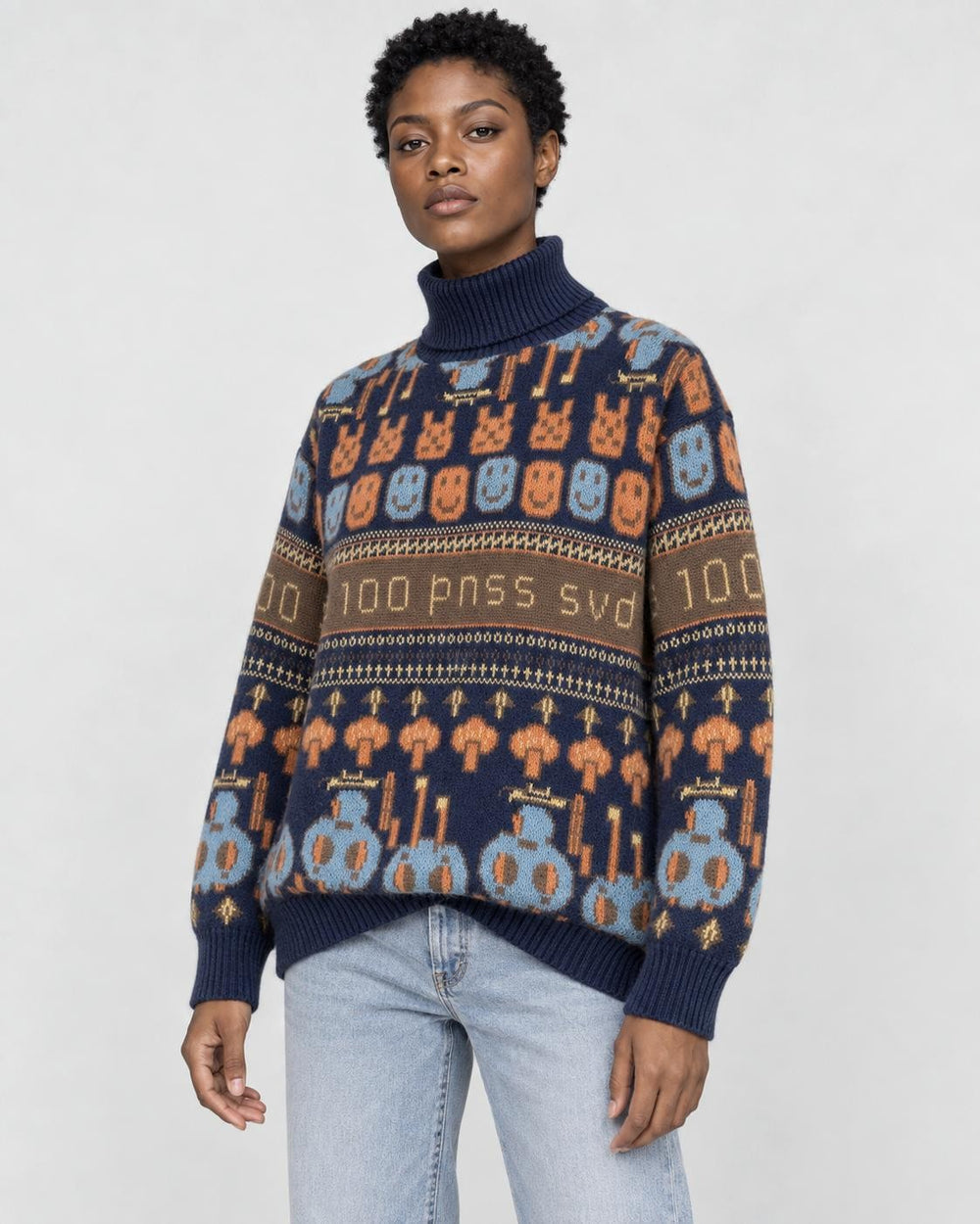 Model wearing the navy jacquard knit sweater with bunny and smiley face rows and a brown lettering band, with light jeans