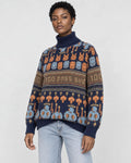 Model wearing the navy jacquard knit sweater with bunny and smiley face rows and a brown lettering band, with light jeans