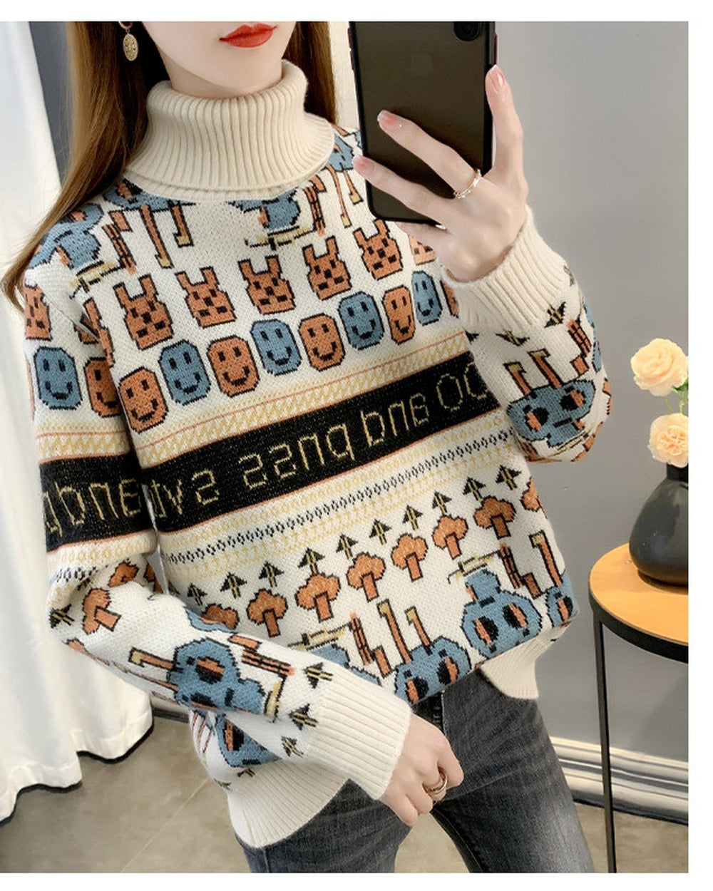 Cream high-neck jacquard knit sweater, front view, with orange mushroom trees and large blue figures above the hem