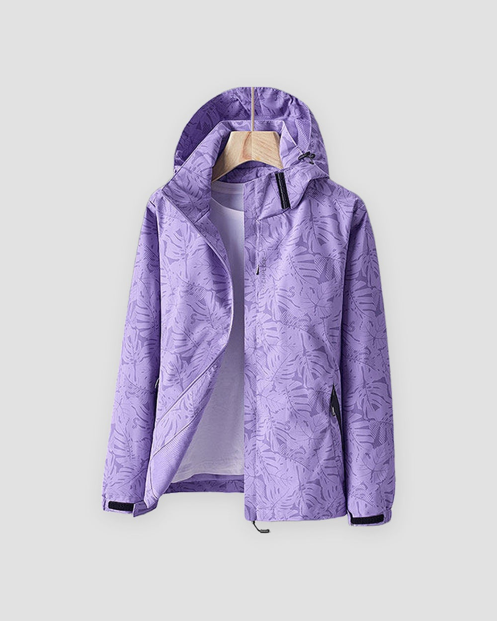 Light purple leaf-print hooded windbreaker with a black collar tab and hook-and-loop cuffs, shown on a hanger