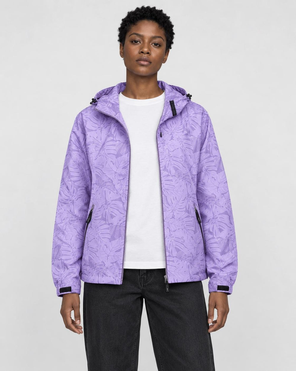 Model wearing the light purple leaf-print hooded windbreaker open over a white tee and black jeans, front view