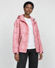 Model wearing the pink leaf-print hooded windbreaker open over a white tee and black jeans, three-quarter view