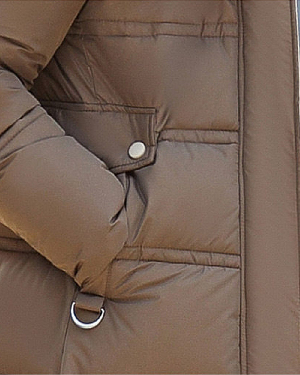 Close-up of a flap pocket with a snap and the small silver ring on the coffee brown puffer coat