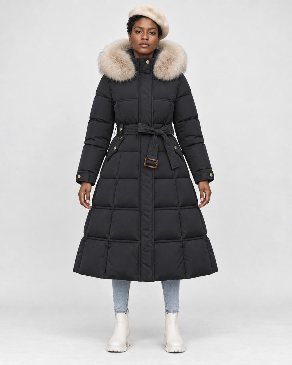 Model wearing the black long puffer coat with a khaki fluffy hood trim and a tie belt, front view