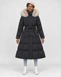 Model wearing the black long puffer coat with a khaki fluffy hood trim and a tie belt, front view