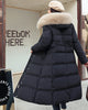 Black long puffer coat seen from behind with a khaki hood trim and a belt, worn with a brown shoulder bag