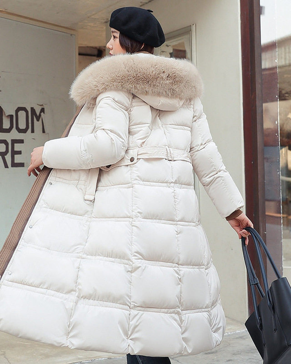 White long puffer coat seen from behind with the khaki hood trim and a belt, worn with a black tote