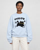 Woman in a light blue loose sweatshirt with a black cat print, cream trousers and white sneakers