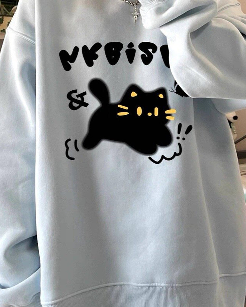 Light blue loose sweatshirt with a black cat print, worn loose, front view