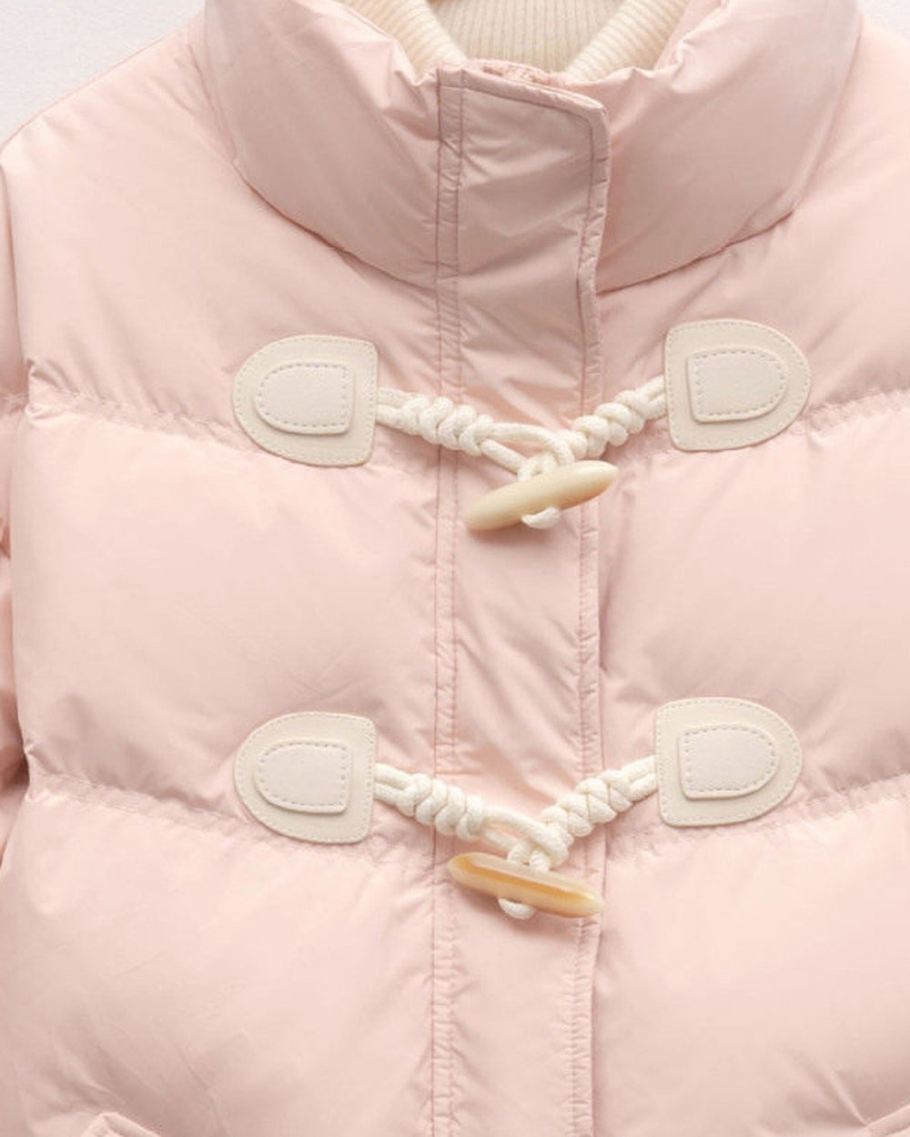 Close view of the two horn toggles on twisted cord loops and the chevron quilting on the pink jacket