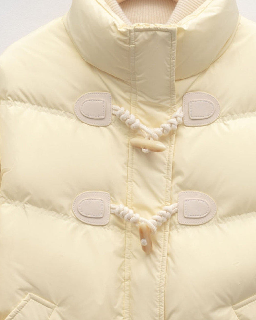 Close view of the two horn toggles on twisted cord loops and the chevron quilting on the pale yellow jacket