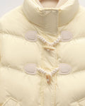 Close view of the two horn toggles on twisted cord loops and the chevron quilting on the pale yellow jacket