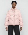 Woman in a short pink puffer jacket with horn toggles over a black top and black trousers, torso to mid-thigh