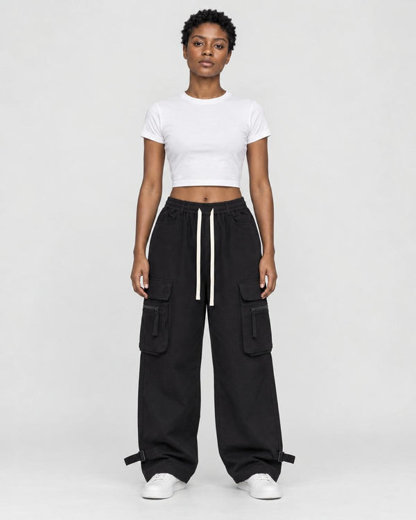 Woman in black wide-leg cargo pants with flap pockets, a white cropped tee and white sneakers, full length