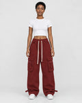 Woman in maroon red wide-leg cargo pants with flap pockets, a white cropped tee and white sneakers