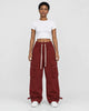 Woman in maroon red wide-leg cargo pants with flap pockets, a white cropped tee and white sneakers