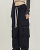 Black wide-leg cargo pants with big thigh pockets and a cream drawcord, worn standing