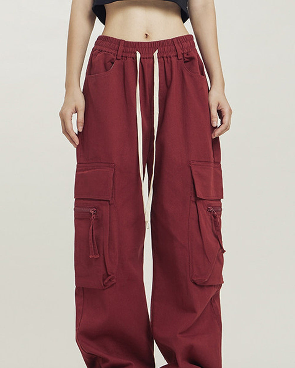 Maroon red wide-leg cargo pants worn standing, showing the thigh pockets and the cream drawcord