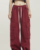 Maroon red wide-leg cargo pants worn standing, showing the thigh pockets and the cream drawcord