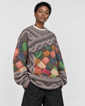 Model wearing the yarn patchwork sweater with wide black trousers, three-quarter view