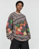 Model wearing the yarn patchwork sweater with wide black trousers, three-quarter view