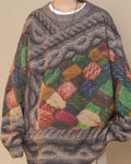 Front of the yarn patchwork sweater with the gray-lilac cable across the shoulders