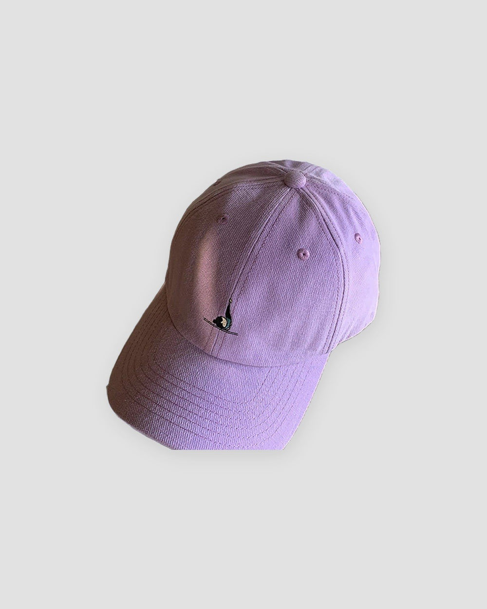 Purple baseball cap with a tiny embroidered yoga figure, three-quarter view