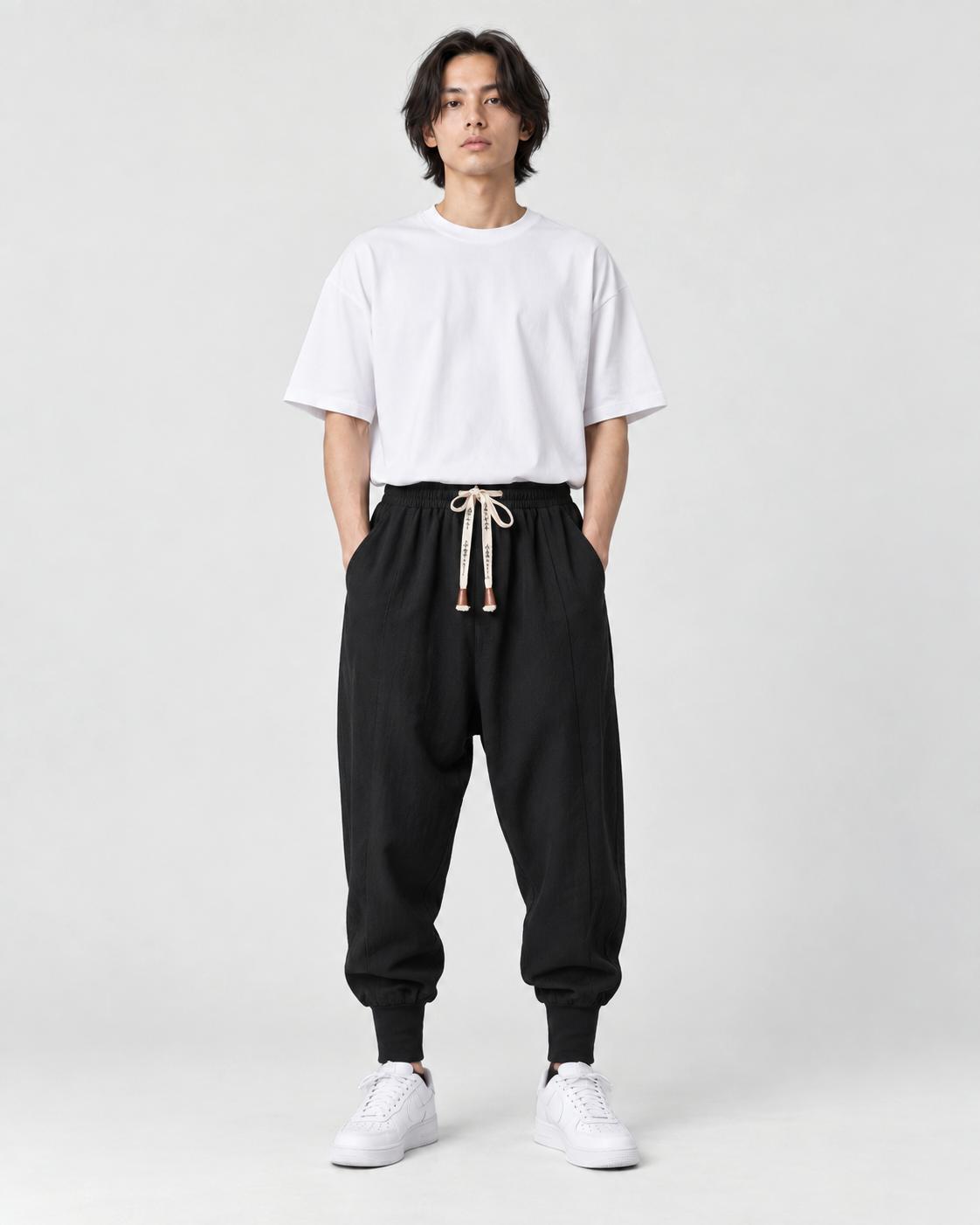 Model wearing black drawstring harem pants with a white T-shirt and white trainers