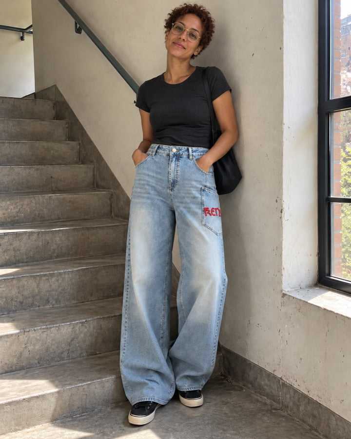 Women's High-Waisted Wide-Leg Jeans with Embroidered Red Pocket Lettering styled for an everyday setting.
